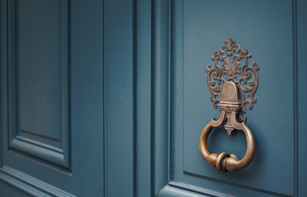 Porte bronze ornée sur porte bleue hôtel particulier luxe Paris rénové