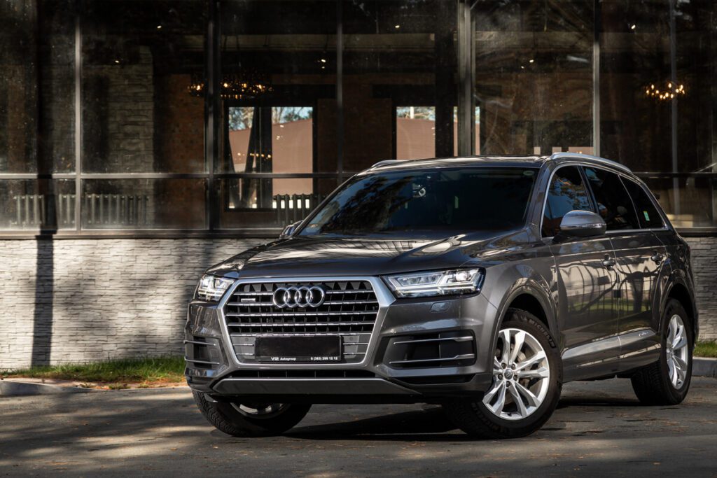 Audi Q7 gris foncé impeccable restituée leasing devant entrée moderne verre lustre, service conciergerie automobile luxury
