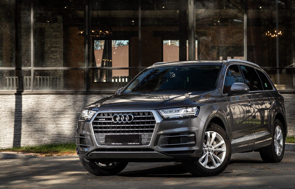 Audi Q7 gris foncé impeccable restituée leasing devant entrée moderne verre lustre, service conciergerie automobile luxury