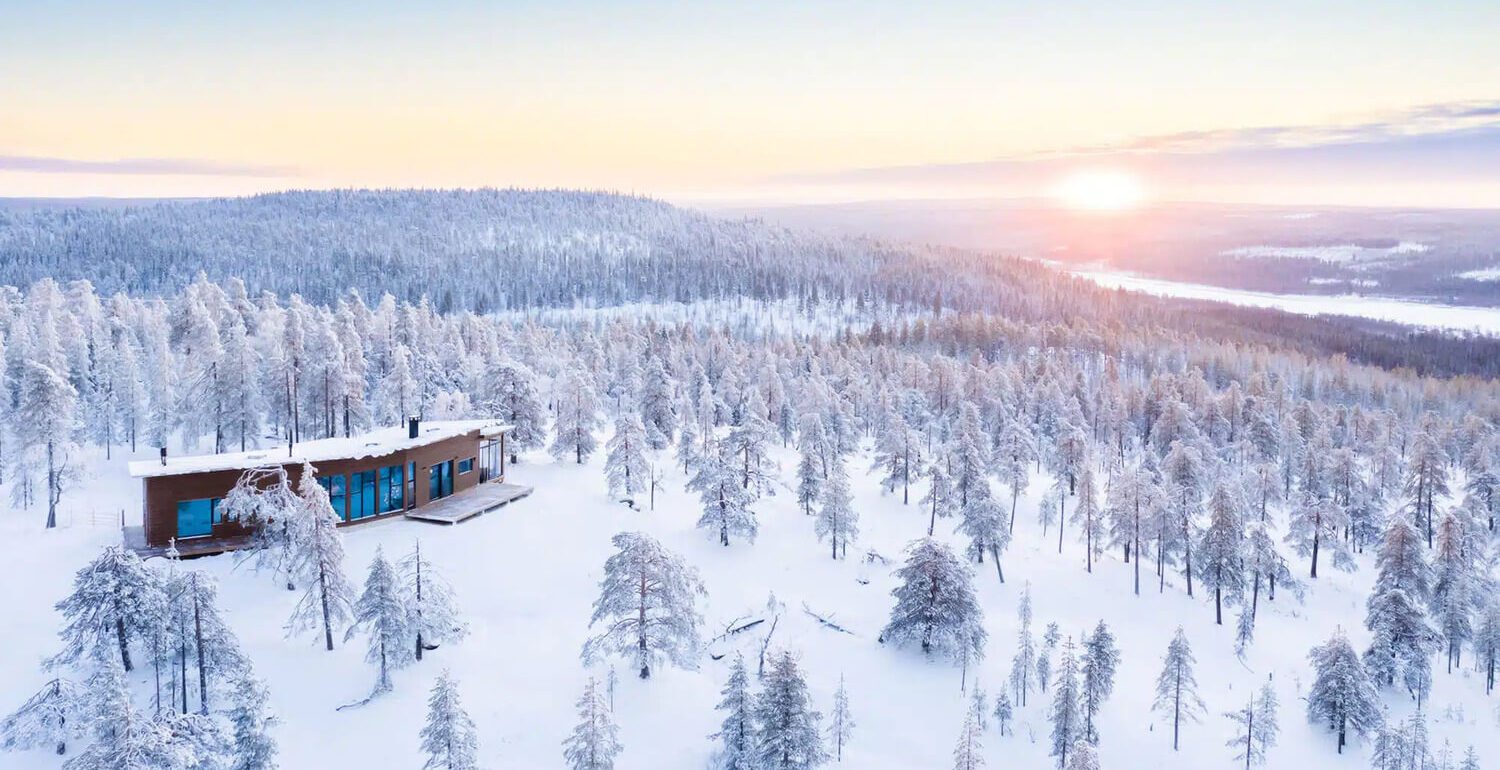 Cabin moderne bois isolée forêt enneigée Laponie Finlande sunset vue lac pour séjour Noël Village Père Noël conciergerie voyages