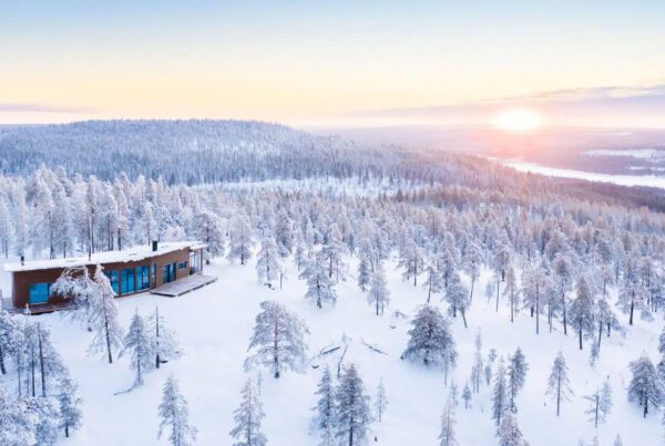 Cabin moderne bois isolée forêt enneigée Laponie Finlande sunset vue lac pour séjour Noël Village Père Noël conciergerie voyages